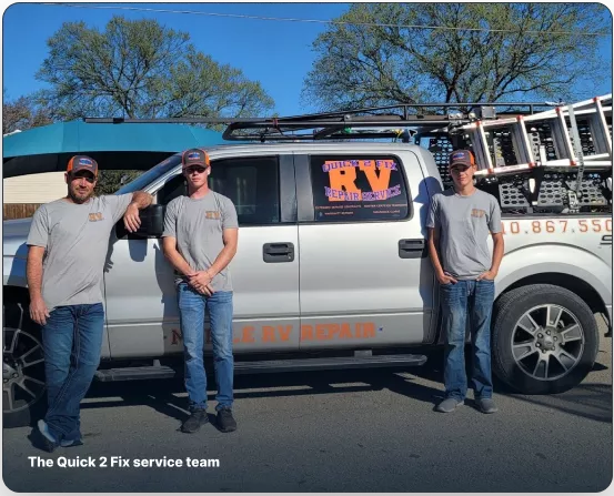 The Quick 2 Fix service team standing beside their silver mobile repair truck equipped with ladder racks.